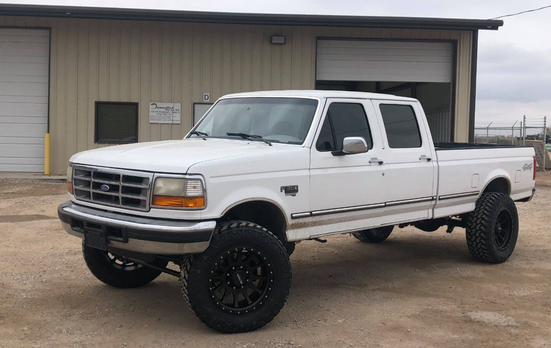 White lifted Ford truck in front of the shop