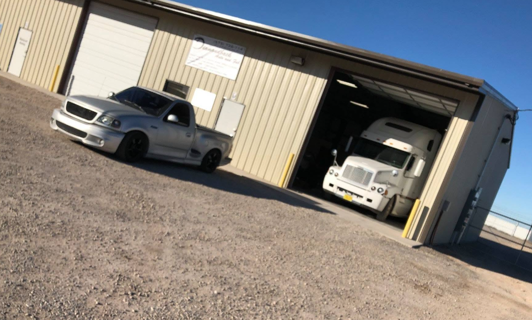Shop exterior with a silver pickup and semi truck