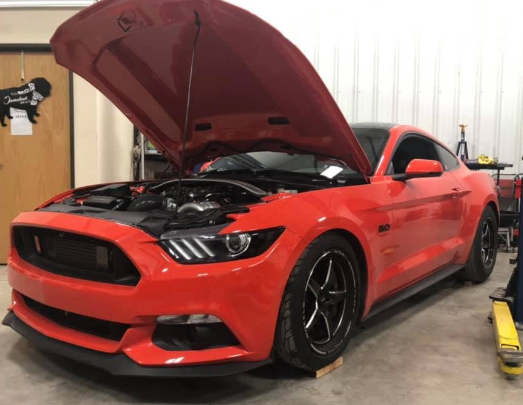 Red Ford Mustang with hood open in the shop