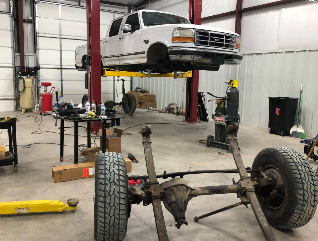 White Ford truck raised on a lift
